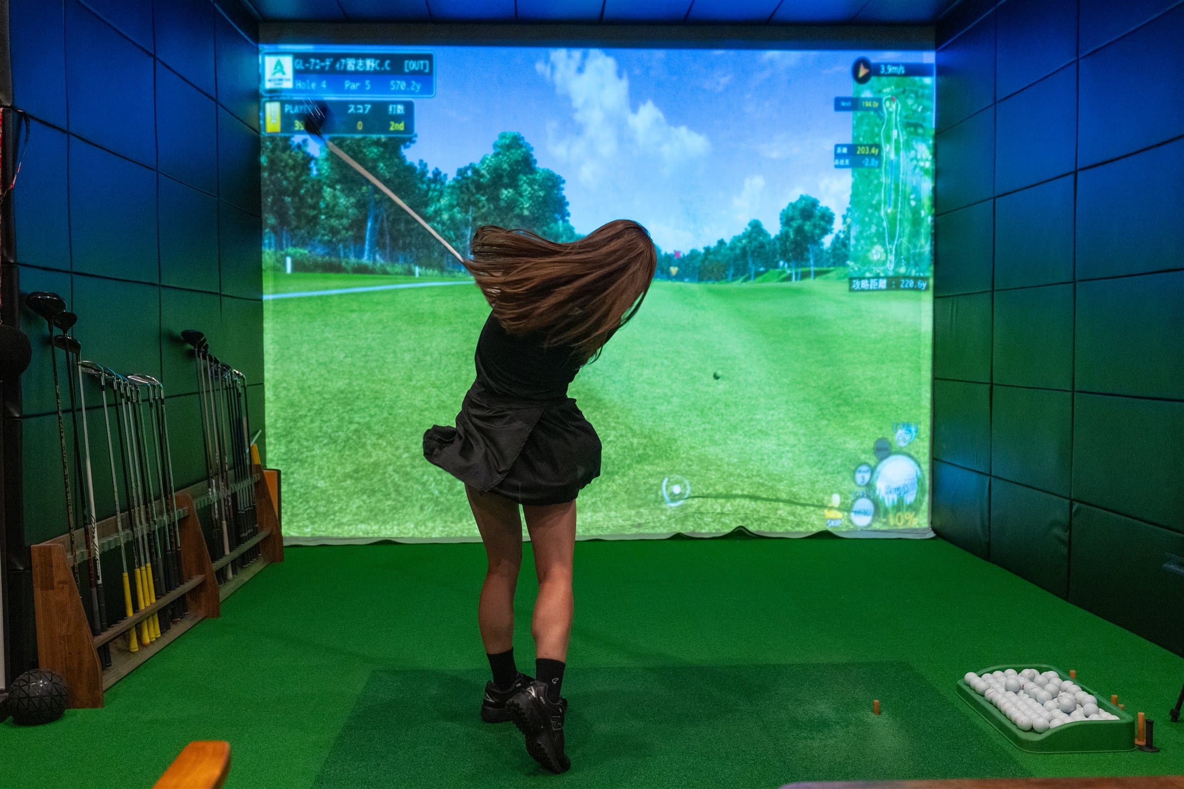 シミュレーションゴルフでショットするプレイヤー