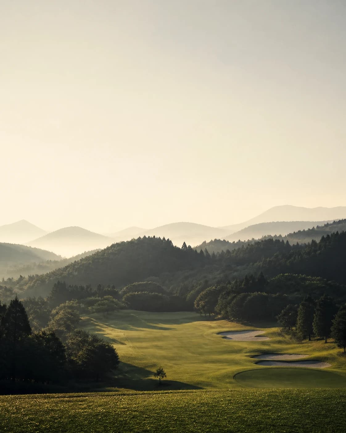 朝の光に包まれた山間のゴルフ場